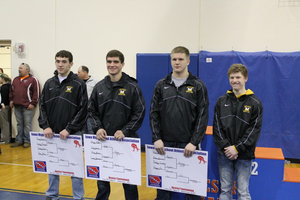 Wrestlers posing with tournament posters